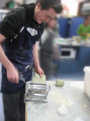 Harry cutting dough to uniform size with a pasta machine