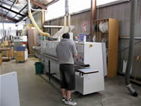 The edge banding machine runs an PVC edge around the cut mdf panels. It applies hot melt to the tape as it is rolled on to the edges, and trims the tape. 